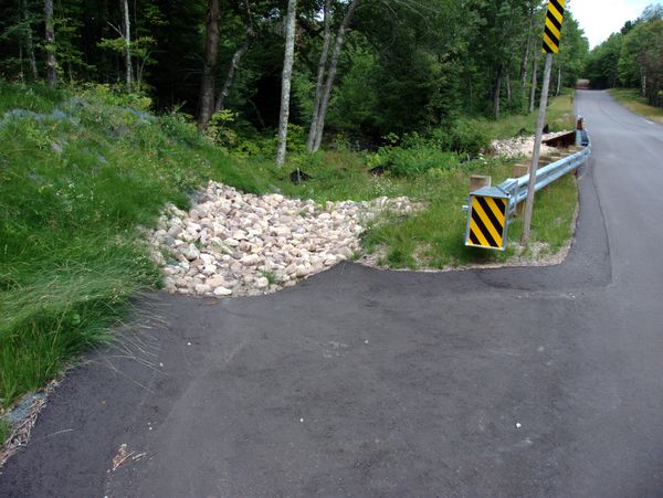 Run off area from the bridge. Notice the rocks and a
		  black retaining fence in the background, both to prevent
		  erosion.