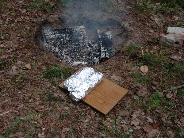 Foil pack dinners of sausage and vegetables ready to be put in the coals.