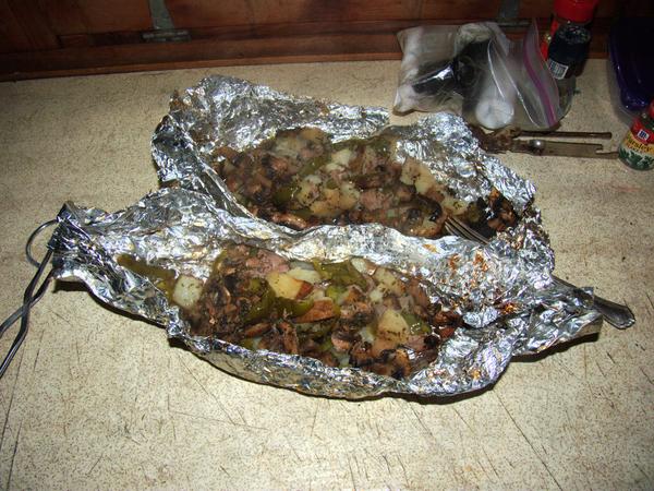 Foil pack dinners of sausage and vegetables out of the coals.