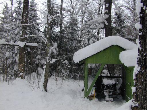 Our snowmobile parked near the wood pile.