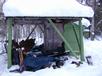 Snowmobile parked near the woodpile.