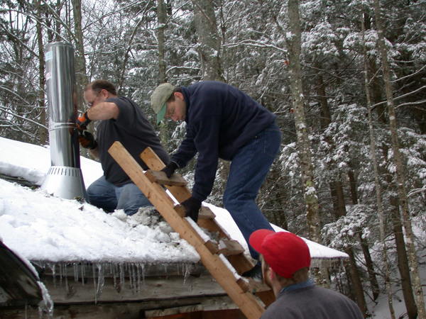 Jon, Bill, and I installing the chimney for the new
		  stove.