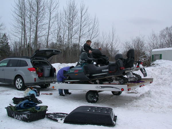 Snowmobiles loaded on the trailers and being secured by Jon and Bill.