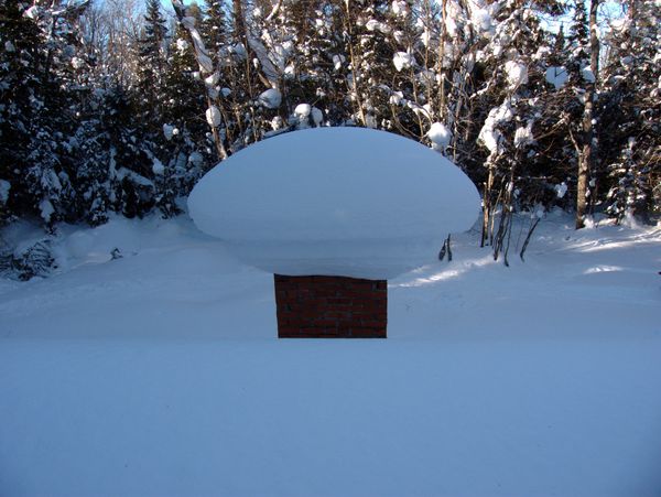 Main chimney for the unused fireplace, covered in snow.