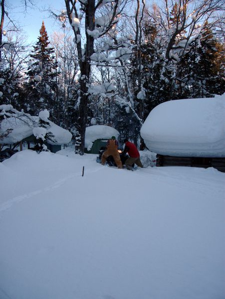 Paul and Doug rescuing the snowmobile from falling off the path near the Cabin.