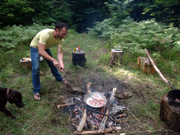 Jordan making paella over the fire with Dog watching.