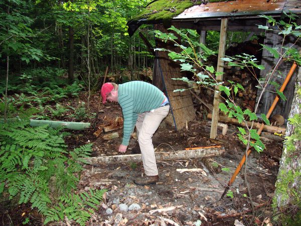 Bill stripping the bark from the temporary support for
		  the wood shed.