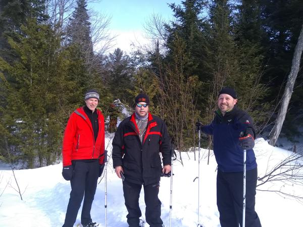 Ed, Mike, and Jim stopped on a snowshoeing trip with Jon in the background.